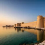 바레인의 역사적 성벽 - **"A majestic wide-angle view of Qal'at al-Bahrain (Bahrain Fort) at sunset. The ancient Portuguese ...